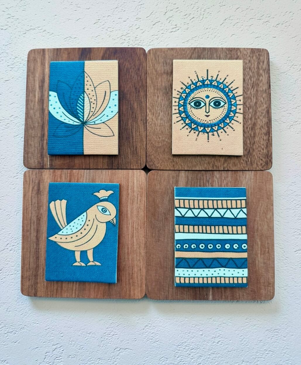 Four wooden coasters with artistic designs on a white background