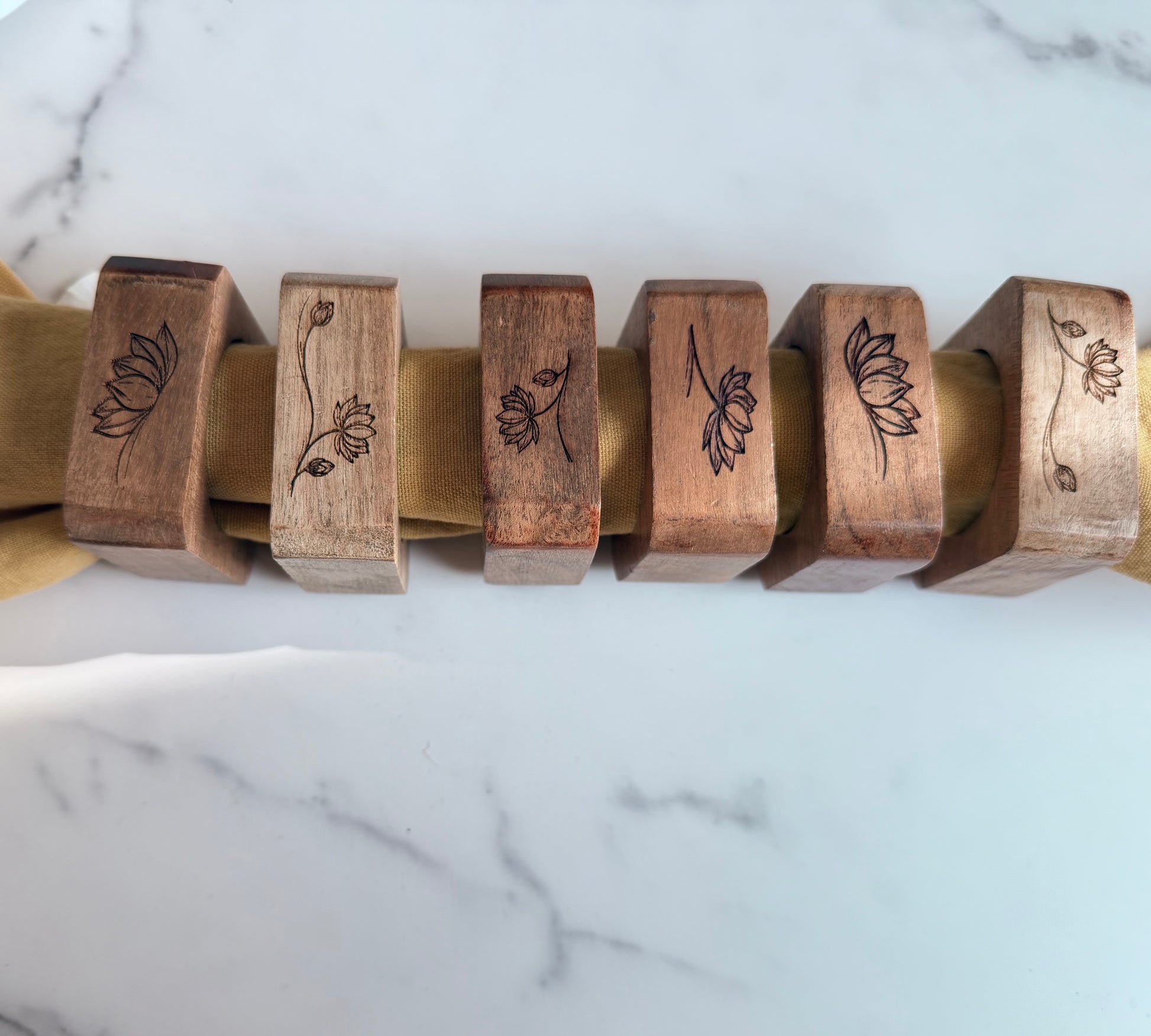 Wooden napkin rings  with floral designs on a marble surface