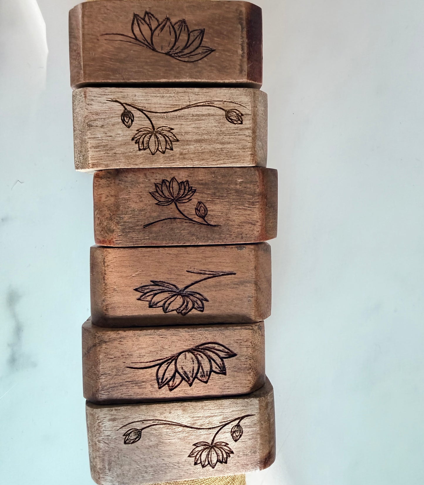 Stack of wooden napkin rings  with engraved floral designs on a light background